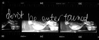 Several frames of 35mm film showing a tabletop setup, handwritten text overlays them which says `don't be entertained`