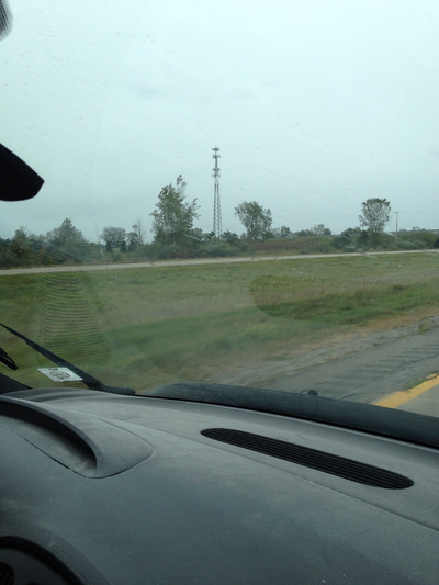 Center grassy area of a highway, through the front window of a moving car