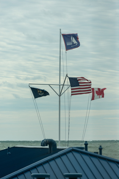 Four flags on a compound pole are fully extended and their ropes are taut