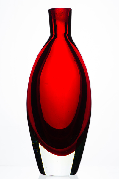 A red bottle that is thick in the middle and nips to a small opening and neck. The base is clear glass and the red color rounds into it. White background.