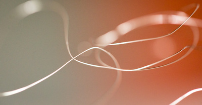 Silvery loops of wire float across an orange and greenish blurred out background